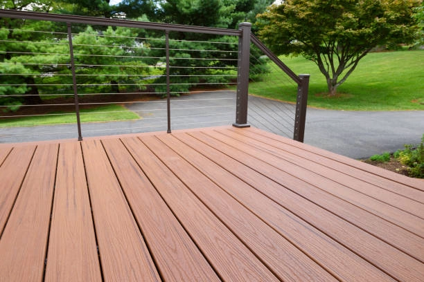 Modern composite deck with sleek railing, overlooking a green landscape. -deck repair services