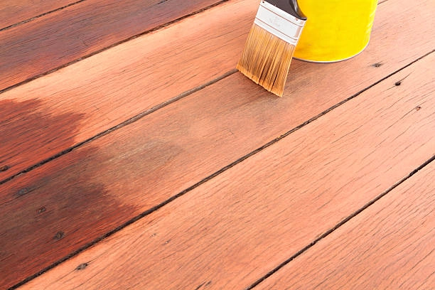 Brush applying wood stain to restore and protect a wooden deck. -deck cleaning services