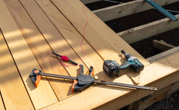 Deck construction site with power drill, clamps, and measurement tools. -deck installation tools