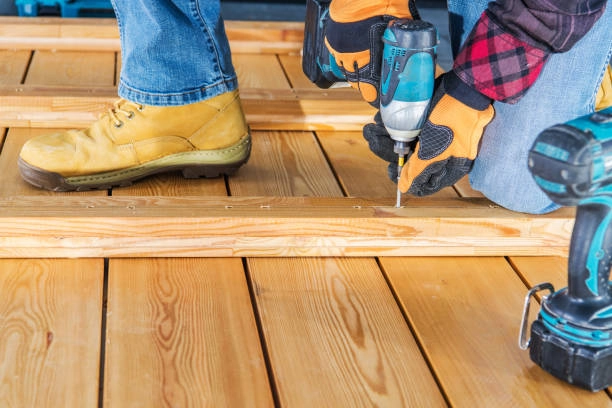 Workers installing wooden deck using power drill and protective gloves. -deck installation tools