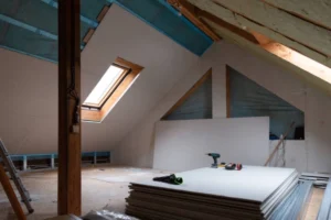 Attic renovation with drywall installation, skylight window, and tools. -home addition contractor