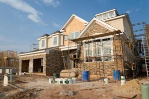 Large modern home under construction with scaffolding and materials outside. -general construction companies