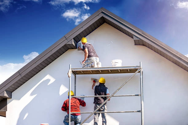 Workers painting house exterior on scaffold under bright blue sky. -what is general construction